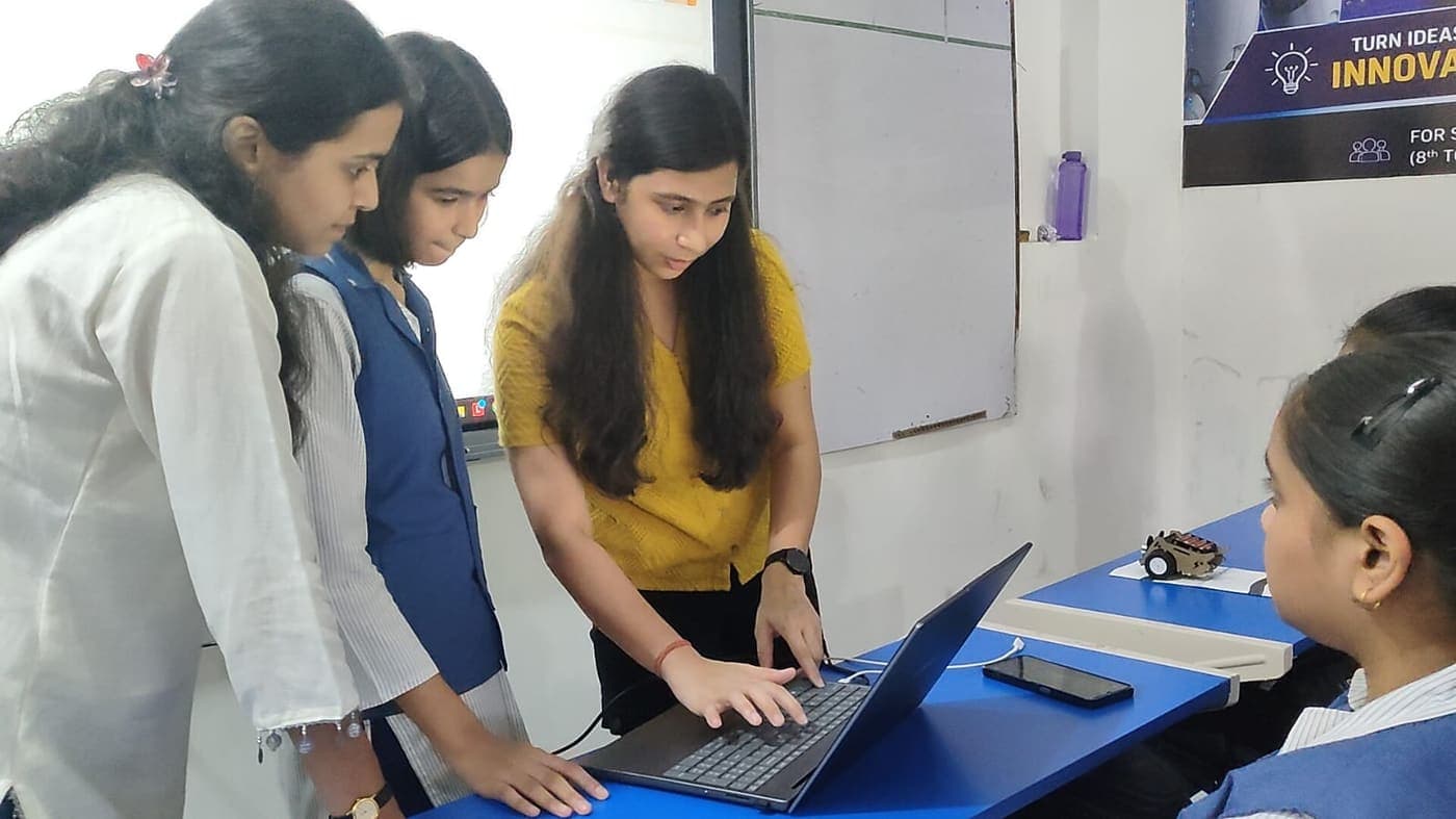 Kajal, SpeakMonk's CEO, working with students at a laptop, with a robot on the desk