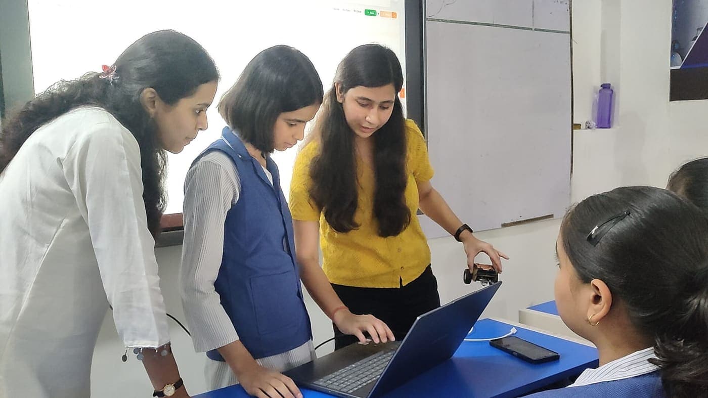 SpeakMonk CEO Kajal and students at a laptop in class, holding a small robot